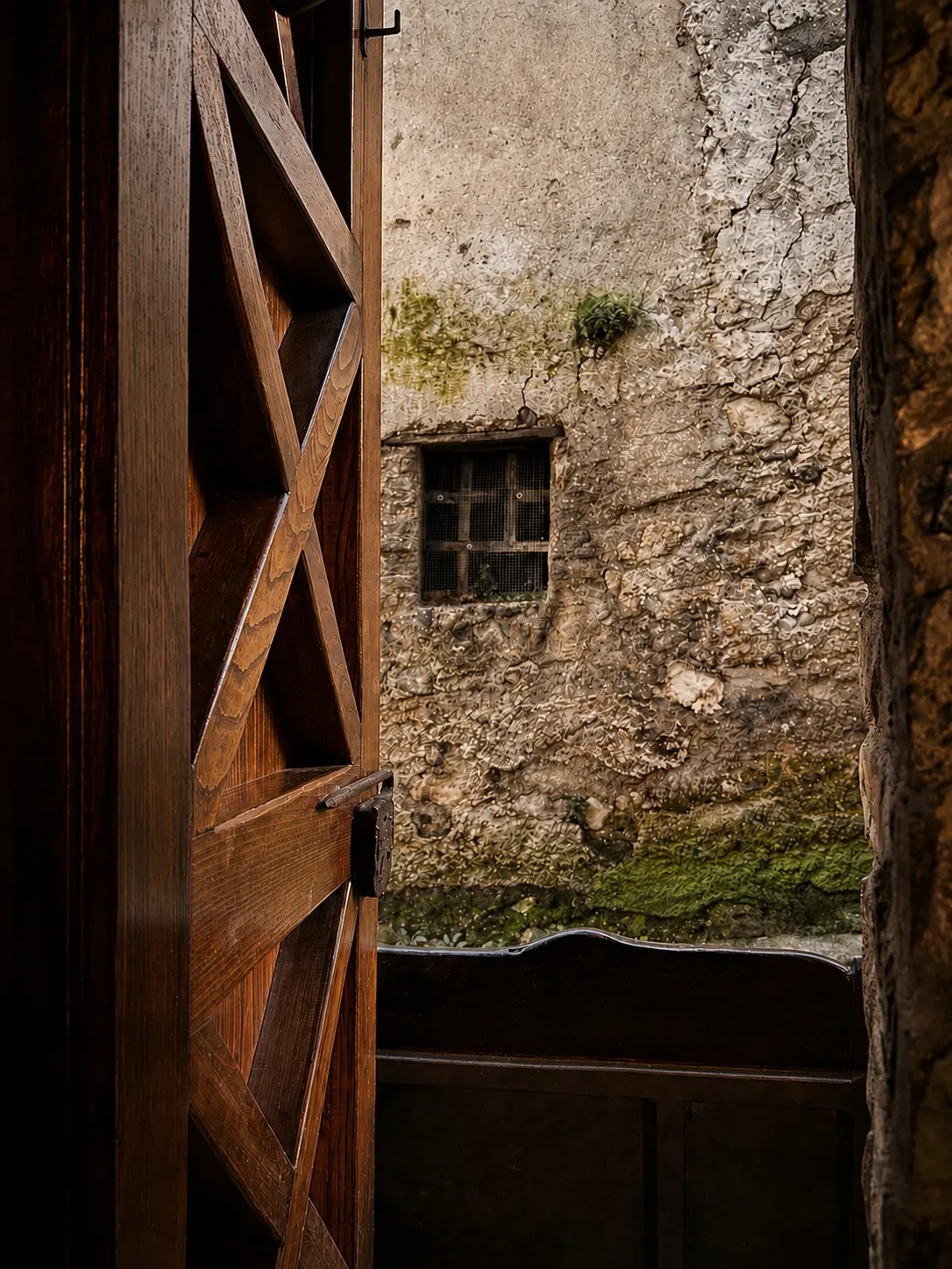 La porta in legno dell'osteria aperta sul muro in pietra del borgo