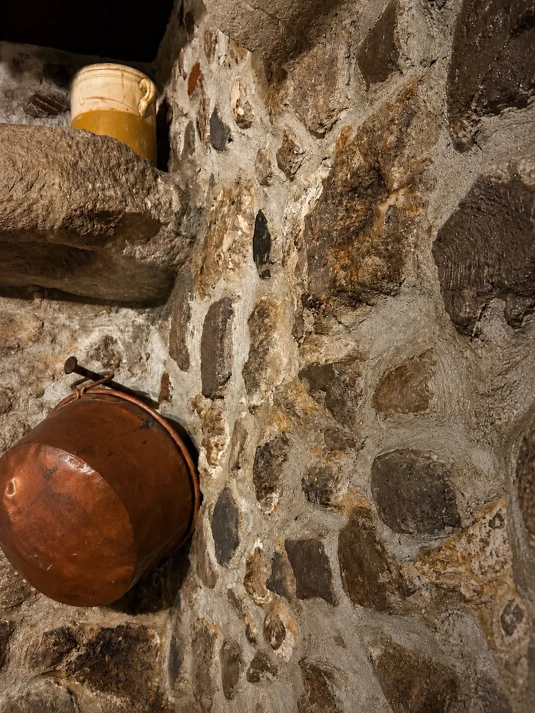 Il paiolo di rame appeso al muro in pietra dell'osteria
